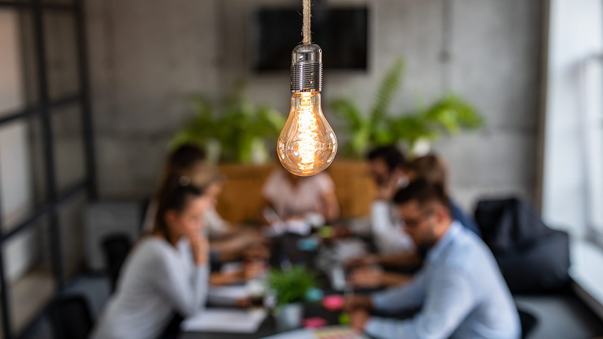 A lightbulb above a busy business meeting.