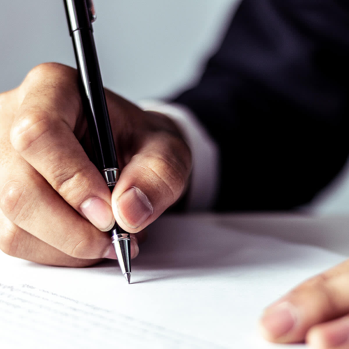 Man holding a pen and wearing a suit