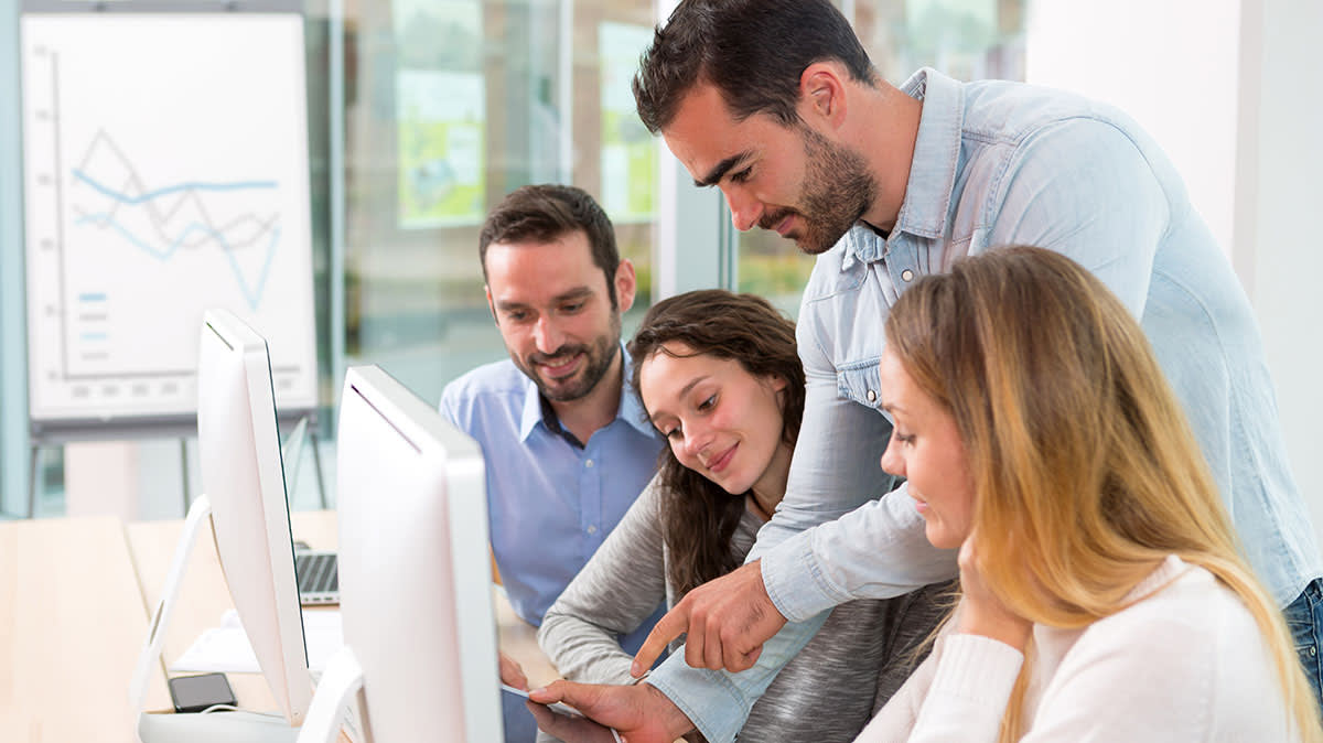 4 people working at computers in a meeting