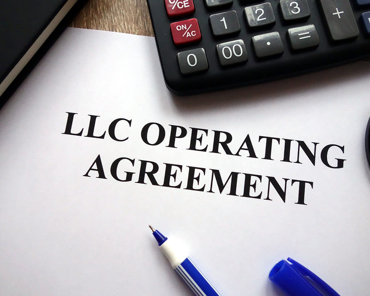 LLC operating agreement, pen, and calculator on desk