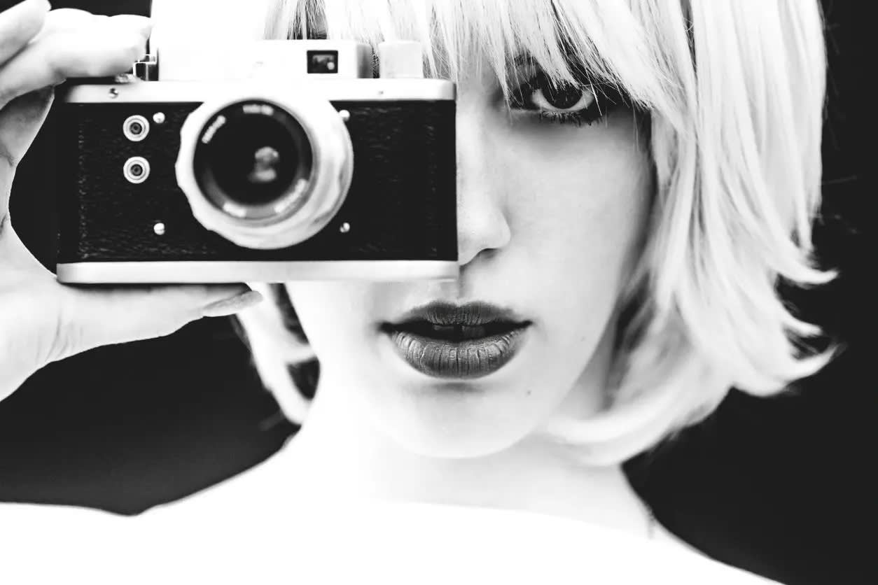 Blonde woman taking a photo in black & White