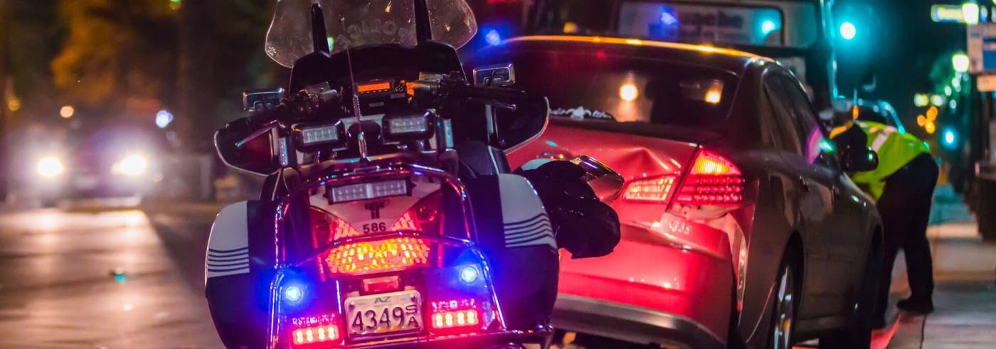 Police bike pulled up to a car accident scene at night