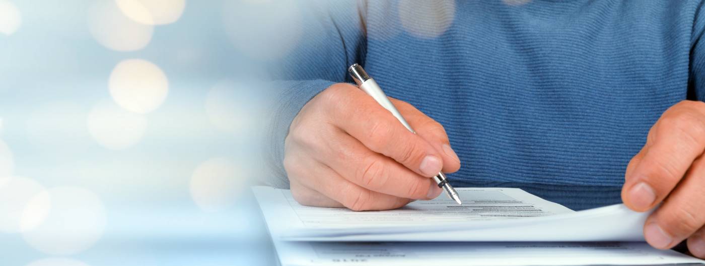 Someone using a pen to sign a document