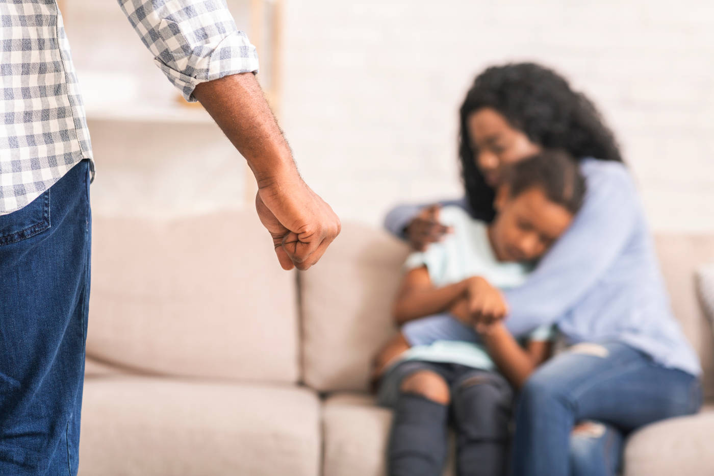 Closed fist of man with scared women and child in background