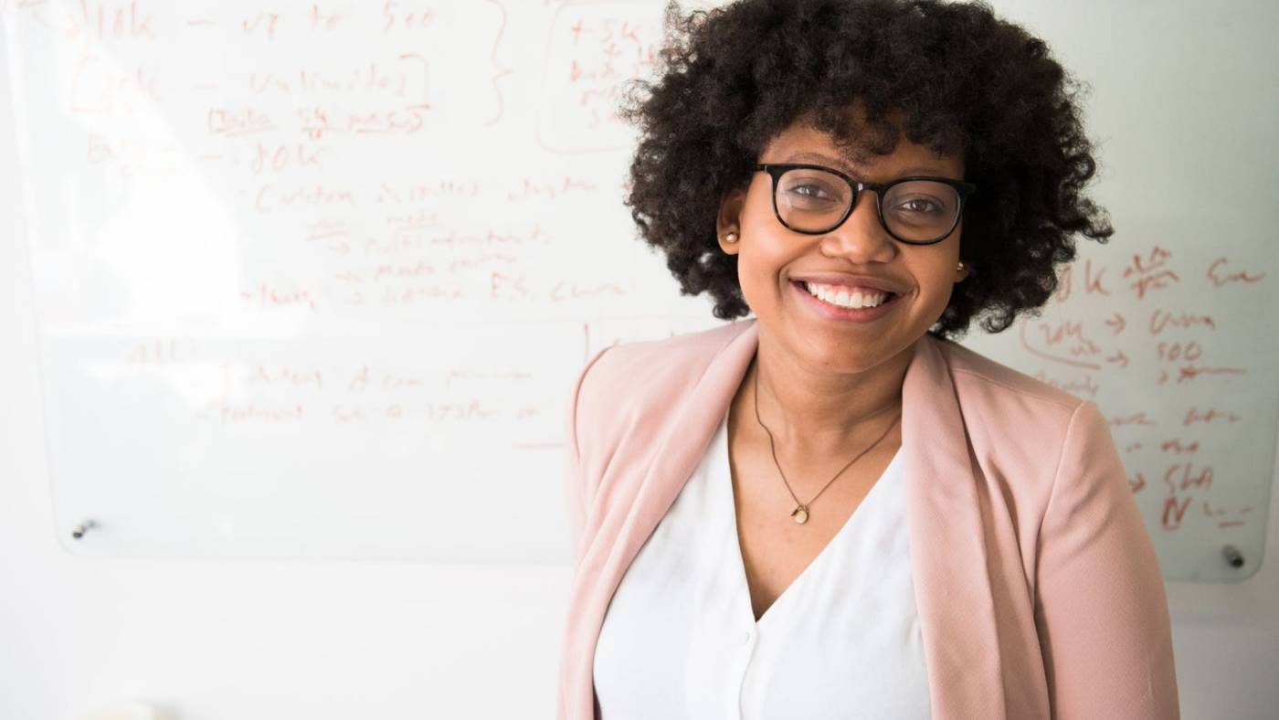 Woman smiling and standing in front of a white board