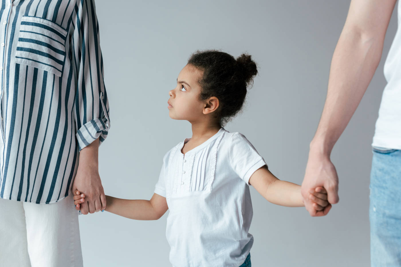 Confused child holding hands of divorced parents