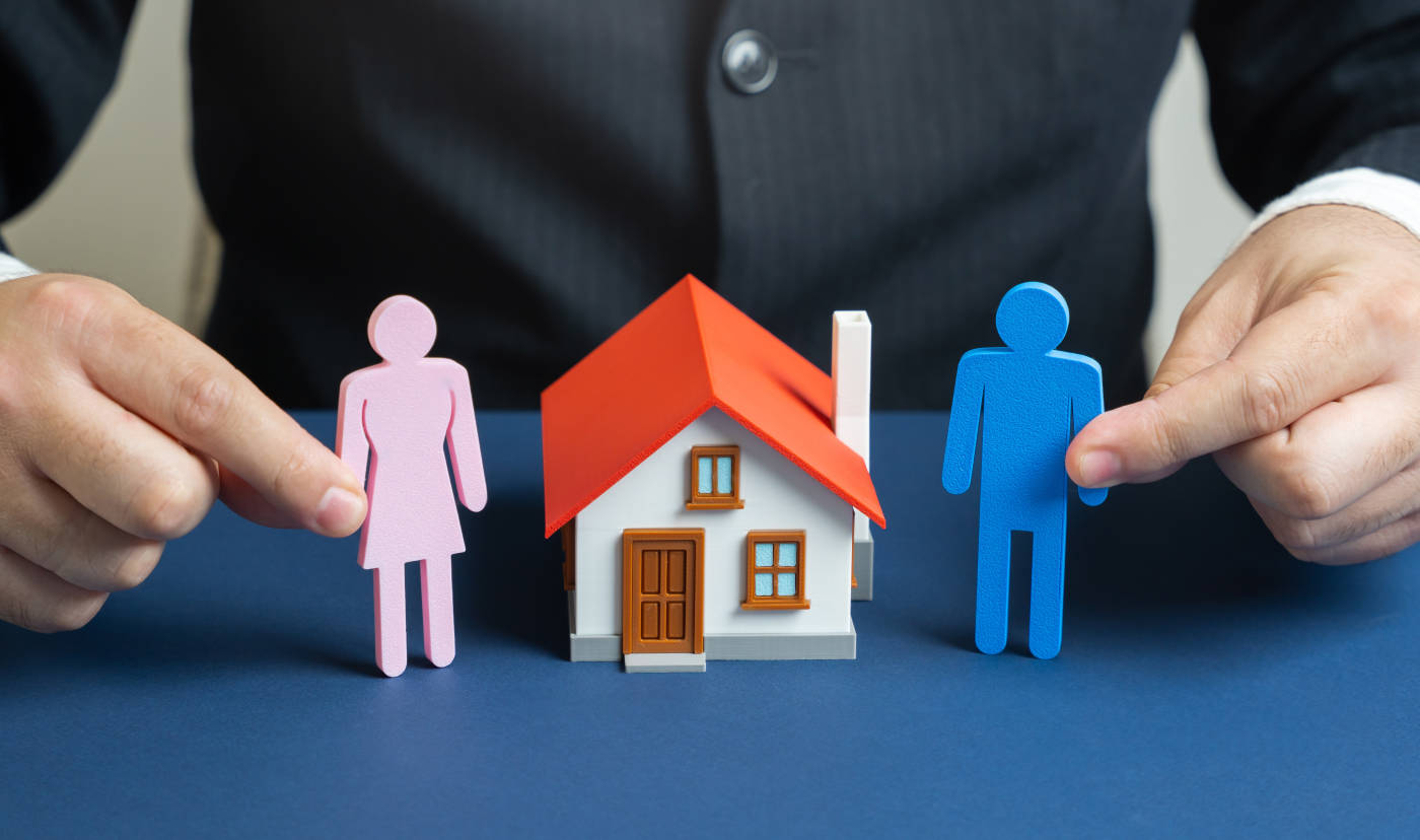 Model house and paper cut out symbolizing property division after divorce