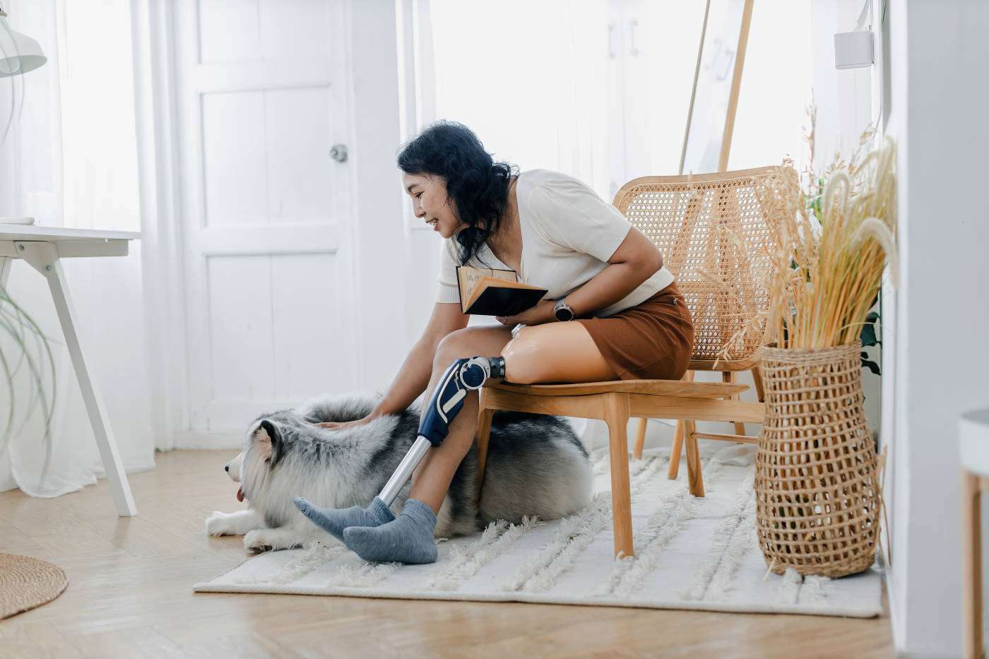Woman with prosthetic leg sitting in chair near dog in home