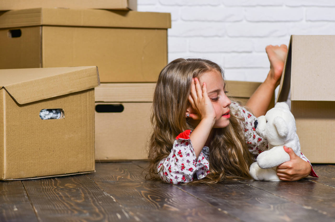Child holding doll among cardboard boxes