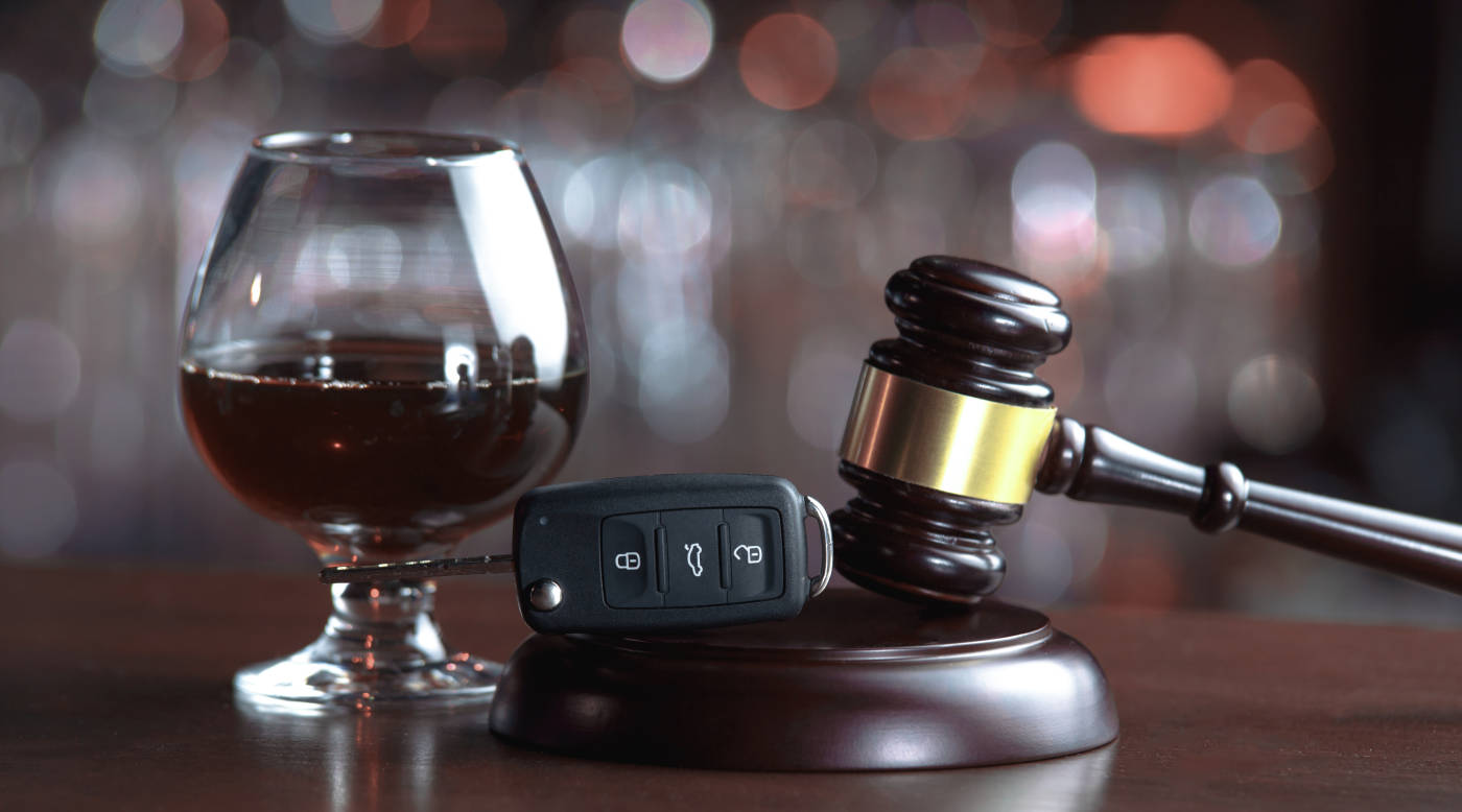 Glass of Alcohol, gavel and car keys in table