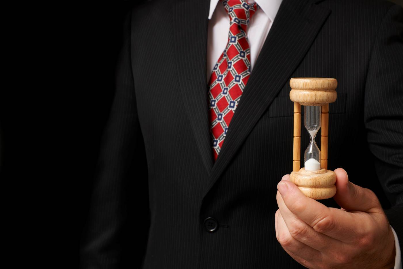 Man in suit holding almost empty hourglass