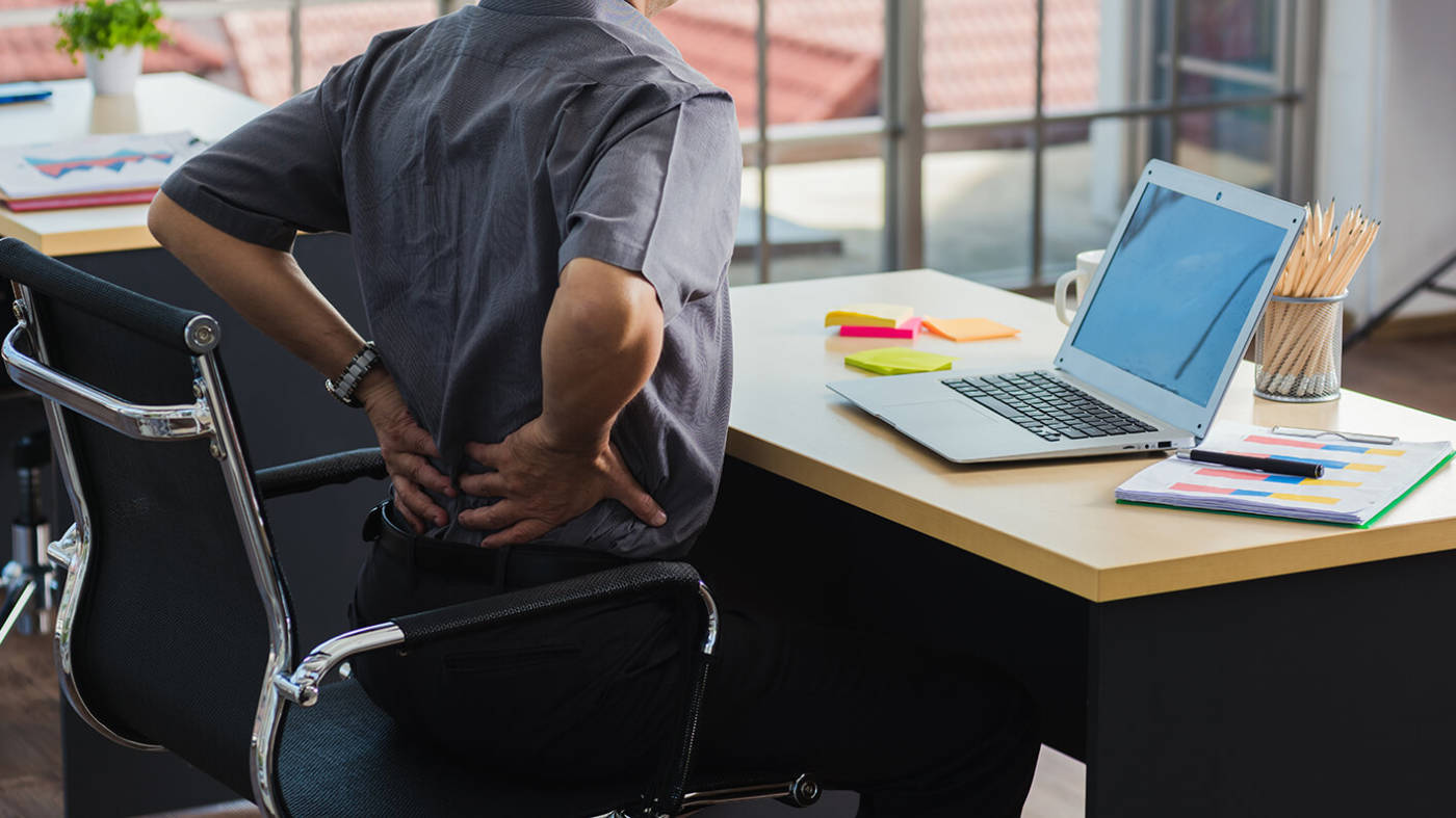 Working man with a sore back sitting at his computer