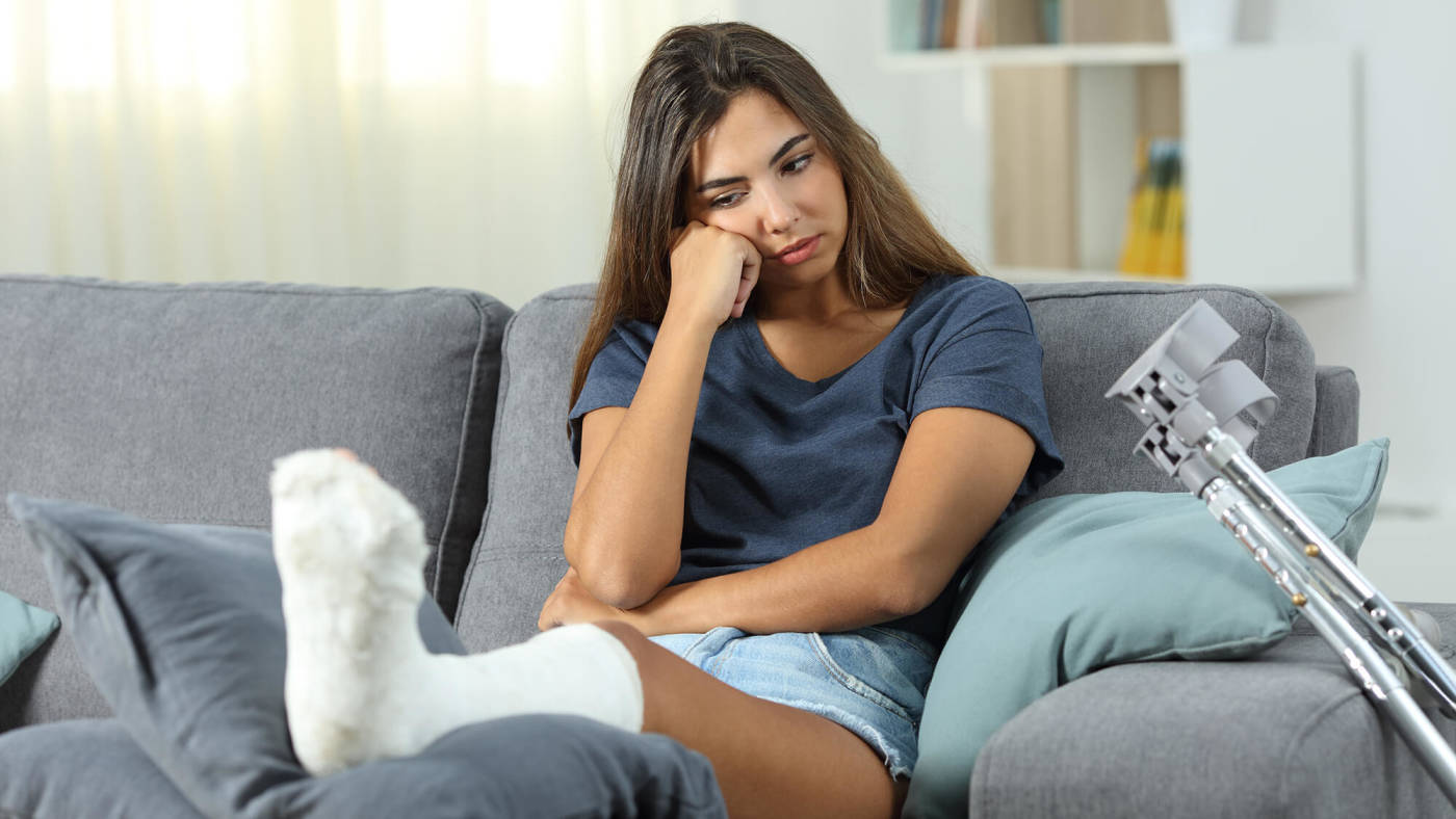 Injured woman sitting on the couch with her leg in a cast