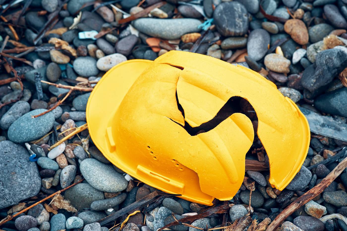 A cracked construction helmet lying on the ground.jpeg
