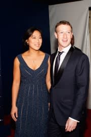 Priscilla Chan pictured in a long navy dress and Mark Zuckerberg in a suit smiling for a photo at the Breakthrough Prize Awards Ceremony