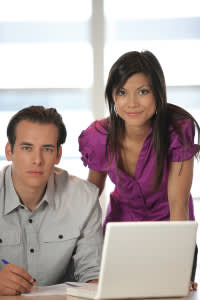 Two business people working by laptop