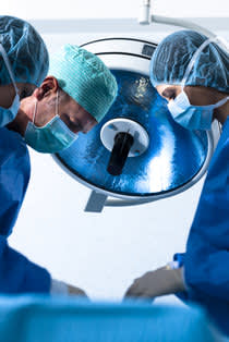 Three doctors looking over a surgery table
