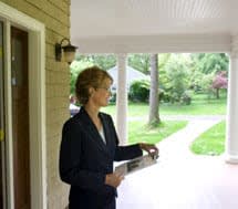 Woman holding clipboard on the porch of a house