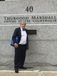 Man in suit holding bag in front of Thurgood Marshall United States Courthouse building