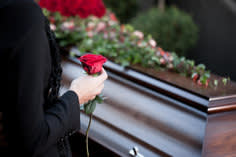 Woman holding a rose over a coffin