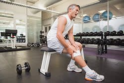 Man in a gym holding his knee in pain