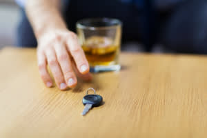 Hand holding a glass of alcohol near car keys