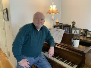 John Foley sitting at piano in his home