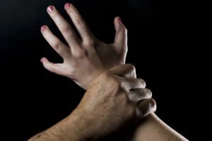 man's hand grabbing woman's arm