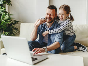 Happy father and daughter surfing the internet on a laptop