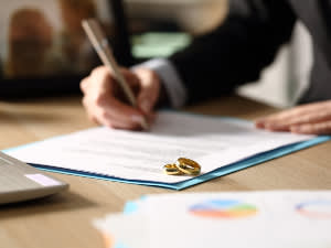 Attorney signing documents with wedding rings on top of the document