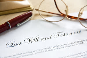 Last will and testament document with glasses and pen nearby