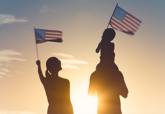 Patriotic man, woman, and child waving American flags in the air.