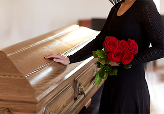 woman with red roses and coffin at funeral