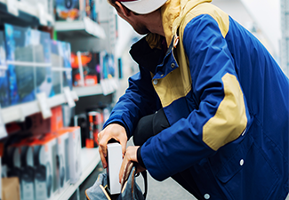 close up consumer thief’s hands putting the new gadget in the pocket in the store