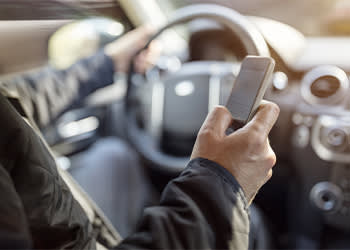 Person driving car and looking at phone