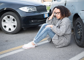 Woman on ground next to car 