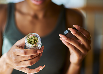 A woman holds a small container of marijuana