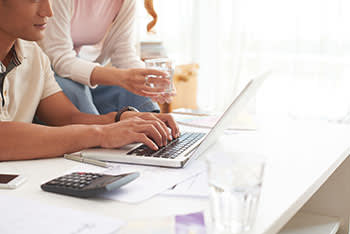 Couple working on laptop with documents and calculator