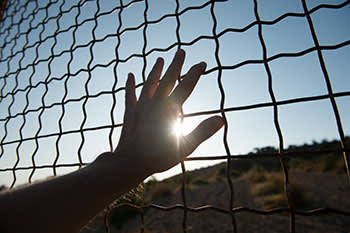 Hand touching the chain link fence