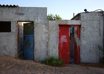 A run down stone structure with a bule door and a red door