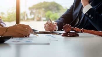 Lawyer sitting at a table with a wooden mallet and paperwork