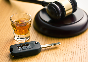 A shot glass, a car key, and a gavel are on a table