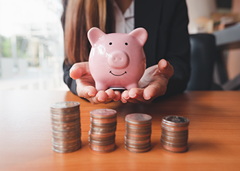 A woman holds a pink piggy bank