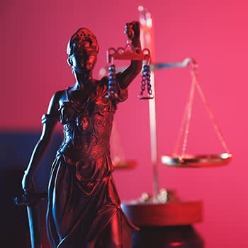 Lady of Justice statue in red neon lighting