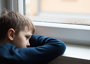 A boy rests his head on a window sill