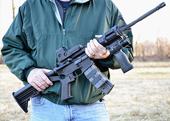 A man holds a large gun outside