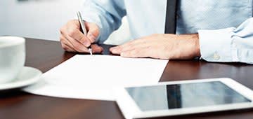 Person in dress shirt and tie writing on document
