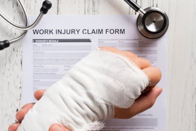 Bandage-wrapped Wrist Over a Work Injury Claim Form 