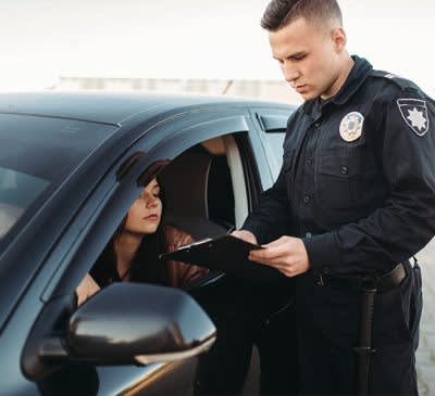 Police officer standing on the driver's side of a woman's car
