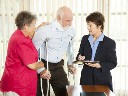 Older couple the man on crutches and in neck brace meeting with lawyer